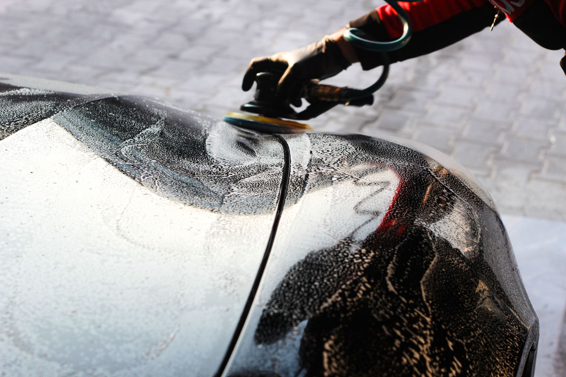 Close-up of a car being polished by hand, showcasing professional detailing and maintenance.