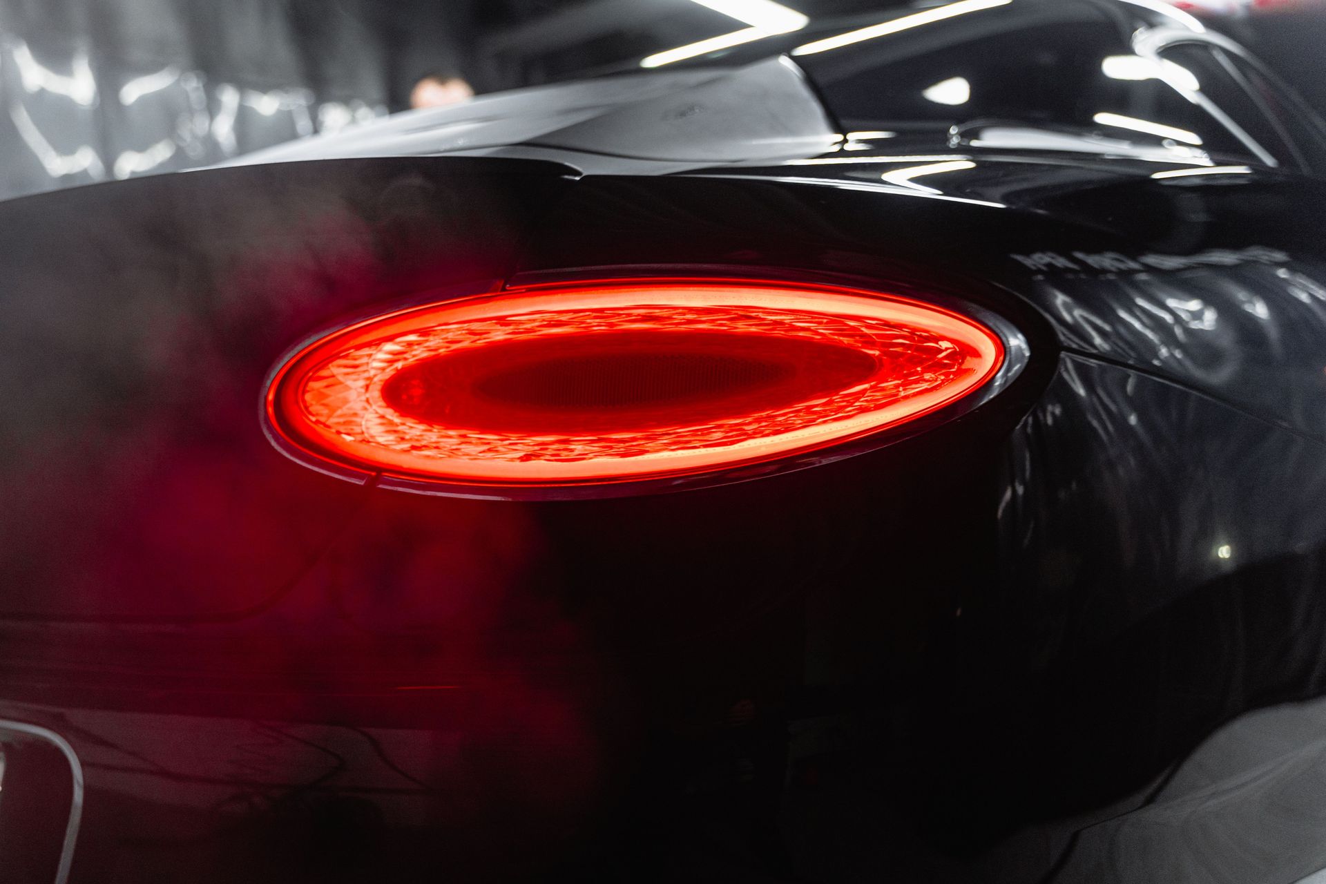 Close-up view highlighting the sleek design of a luxury black car's illuminated tail light.